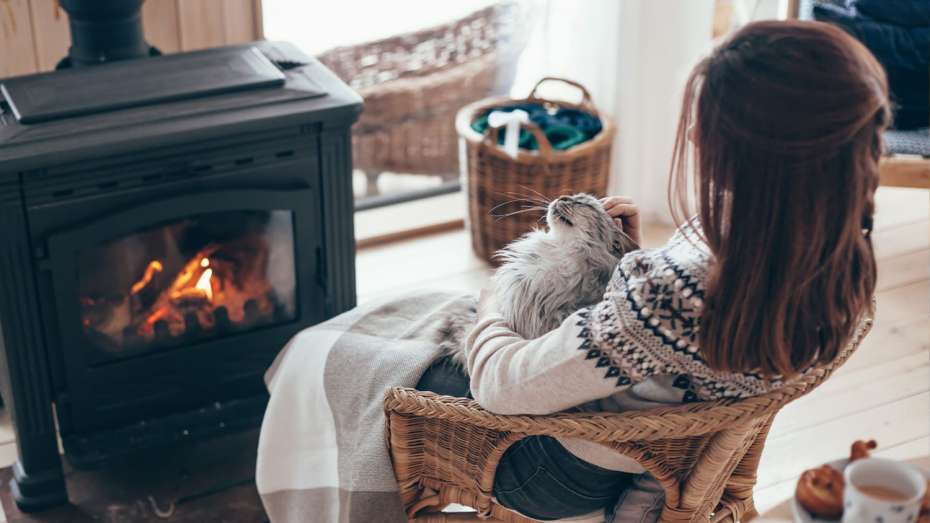 Woman with cat sitting in front of fireplace