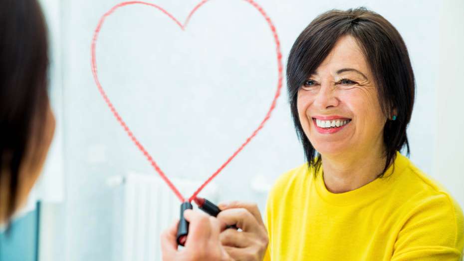 Smiling woman drawing a heart in lipstick on a mirror