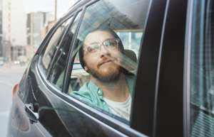 Man in recovery looking out the window on his way to treatment in the back of a car
