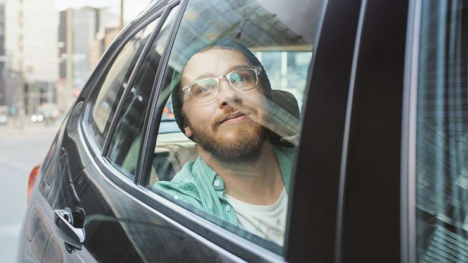 Man in recovery looking out the window on his way to treatment in the back of a car
