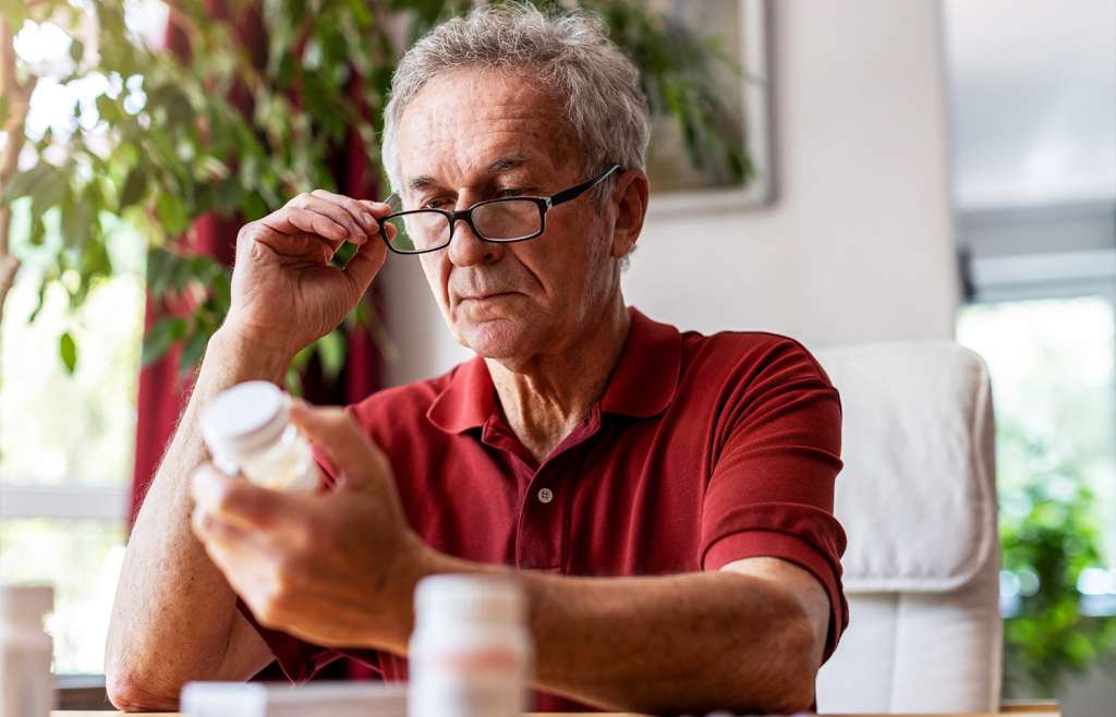 Older male examining old medication bottle