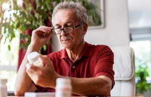 Older male examining old medication bottle