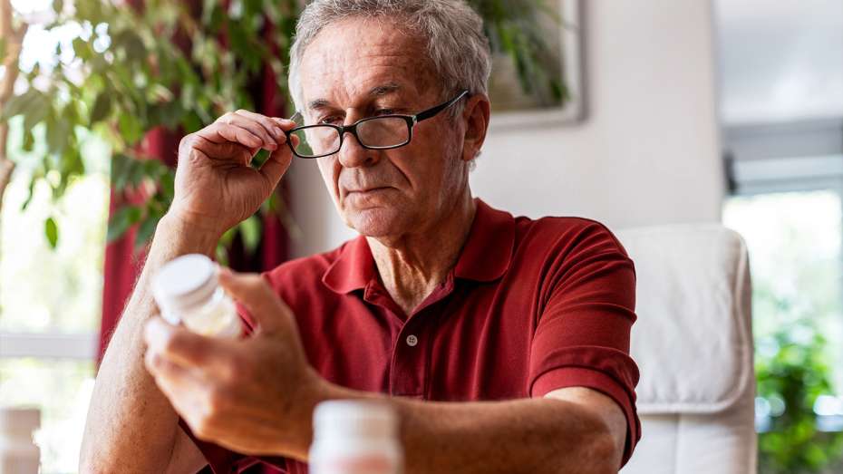 Older male examining old medication bottle