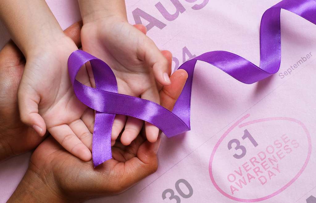 Hands holding purple ribbon for overdose awareness