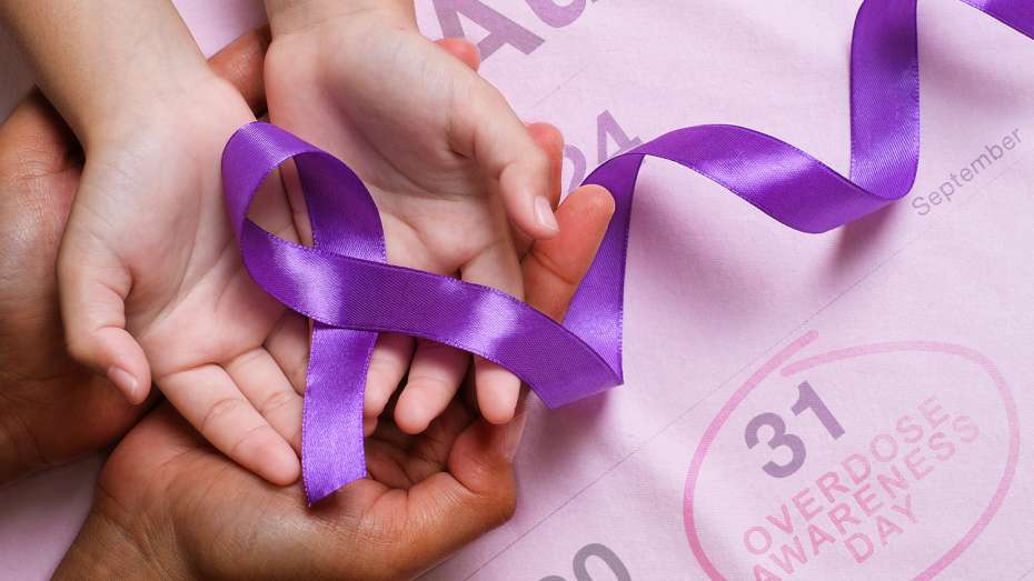 Hands holding purple ribbon for overdose awareness